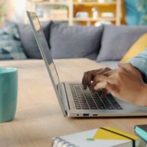 Person typing on a laptop at a wooden desk.